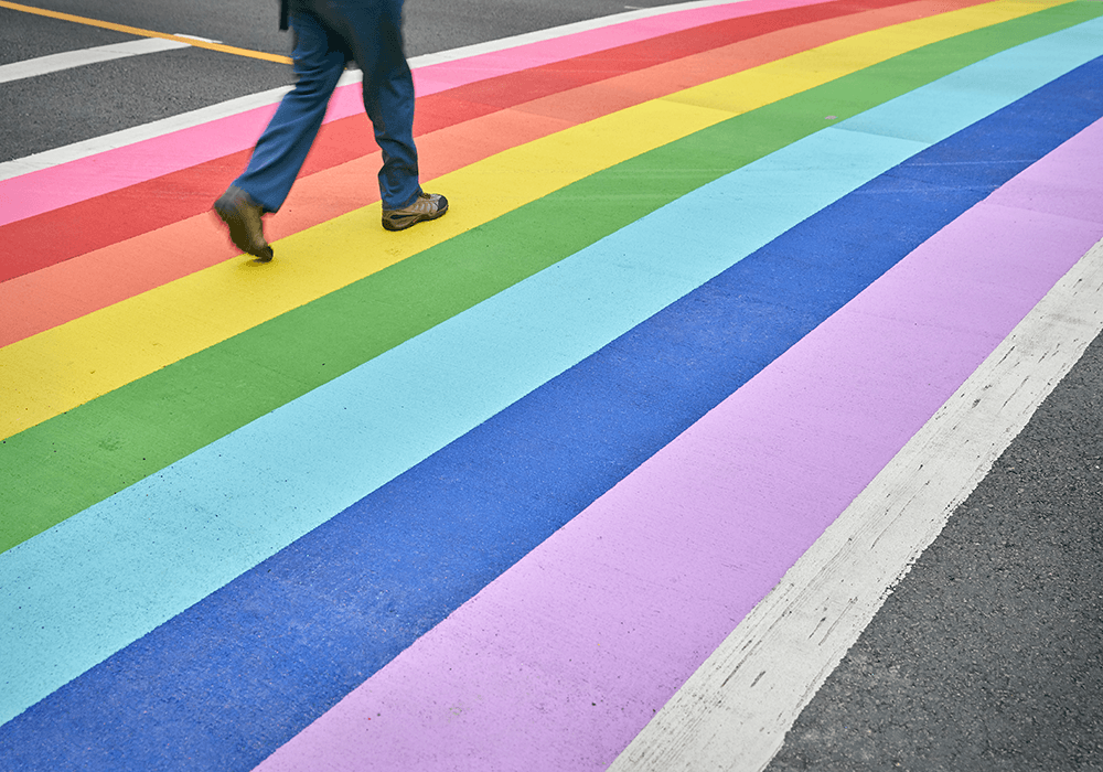 Image of rainbow crosswalk and someone walking on crosswalk